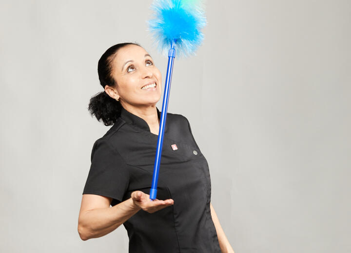 Haushälterin, die mit einem Staubwedel jongliert